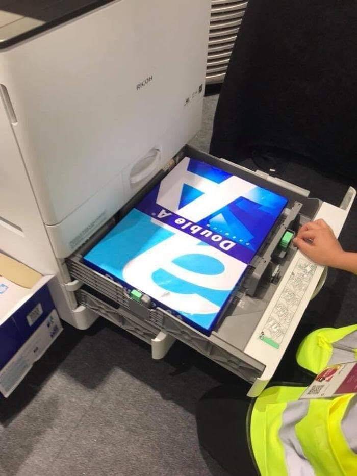 A person loading printer paper upside down into a copier, demonstrating a You Had One Job moment.