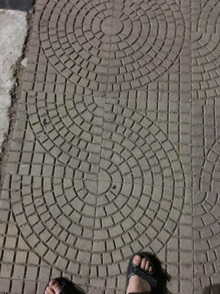 A sidewalk with a poorly laid pattern of circular bricks, illustrating a You Had One Job fail in construction.