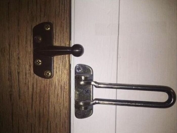 A door security latch is installed on the door frame next to a decorative door stopper, a clear You Had One Job fail.