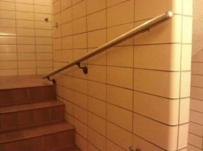 A handrail on a tiled wall that ends too early, showcasing a You Had One Job Fail.