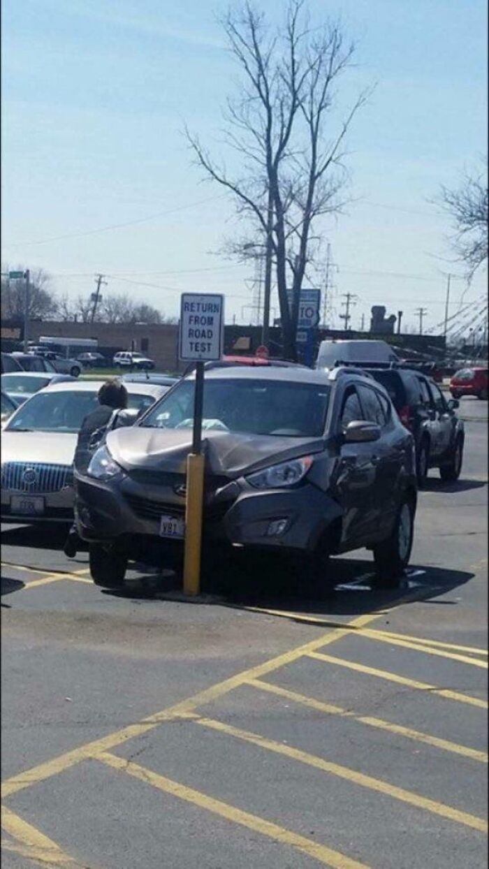 A car crashed into a pole in a parking lot, a perfect example of You Had One Job Fails.