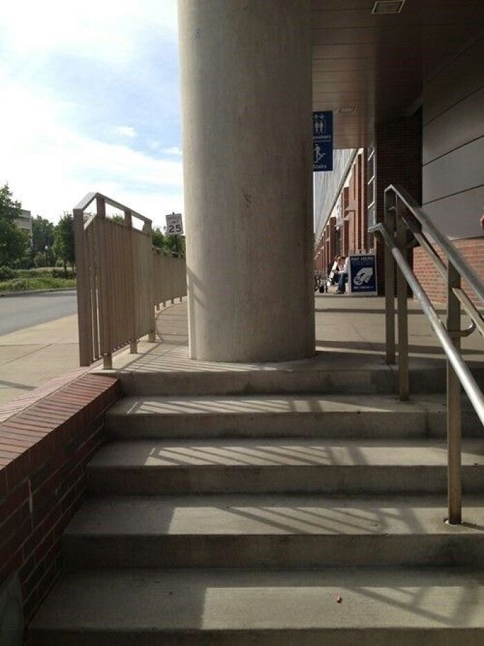 A concrete pillar blocks a sidewalk and stairs, an example of You Had One Job Fails.