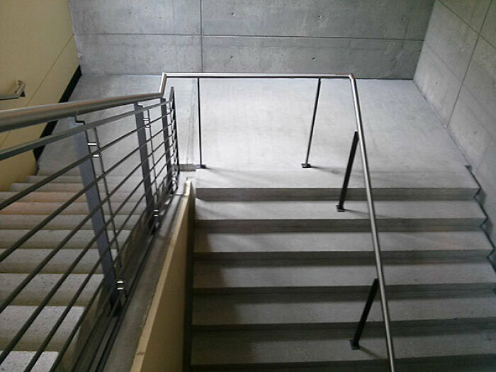 A concrete staircase with a handrail that stops abruptly mid-air, a clear “You Had One Job” fail.