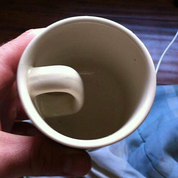 A white ceramic mug with the handle on the inside, demonstrating a You Had One Job fail.