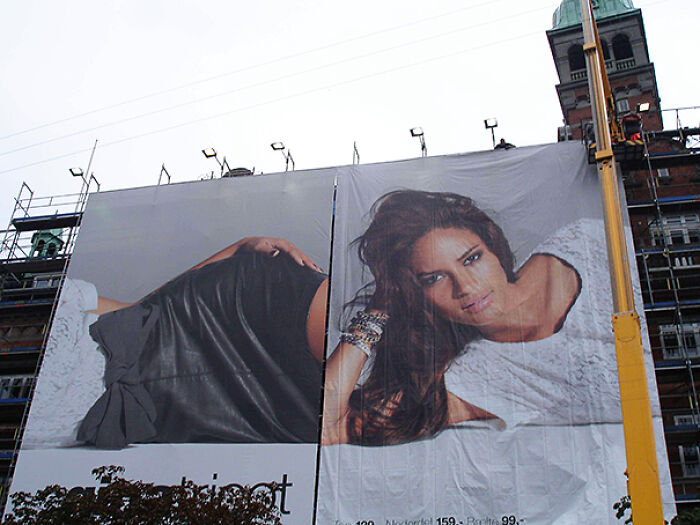 A large billboard displaying a poorly aligned image of a woman, a classic 'You Had One Job' fail.