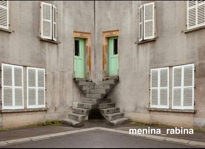 A building with two green doors and diverging staircases, a clear example of 'You Had One Job' fails.