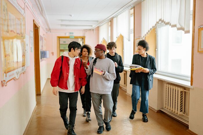 Students walking in a school hallway, one looking thoughtful, realizing something was not a joke.
