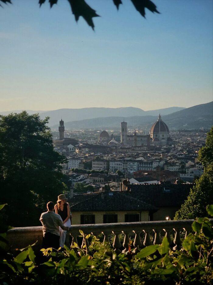 Two people looking at a sprawling city from a viewpoint, like a painting, exemplifying the wholesome photo trend.