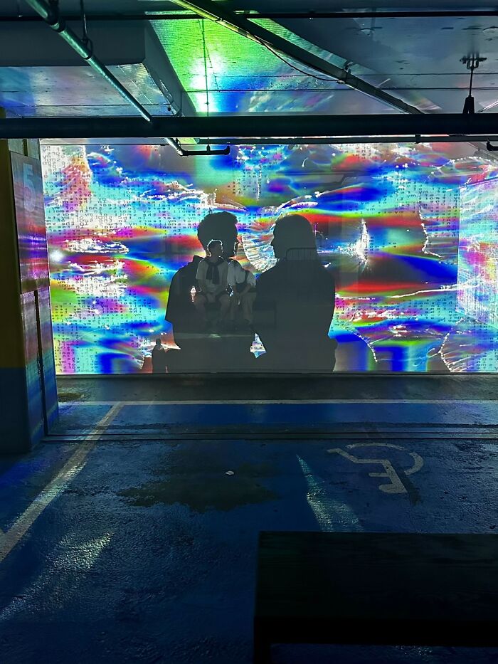 A vibrant photo trend capturing two silhouettes against a colorful, abstract light display in a parking garage.