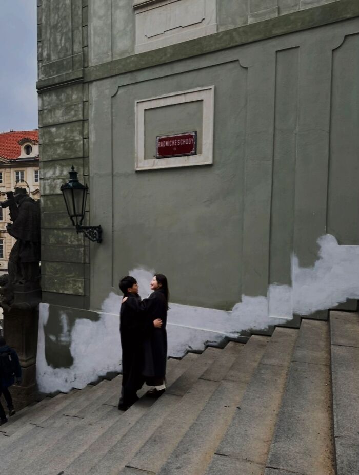 A couple embracing on stone steps, captured in the 'Like A Painting' photo trend between strangers.