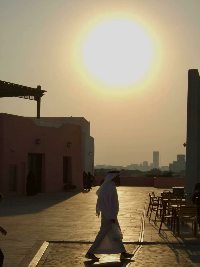 A wholesome photo of a person in traditional attire walking under a bright sun, a beautiful example of the photo trend.