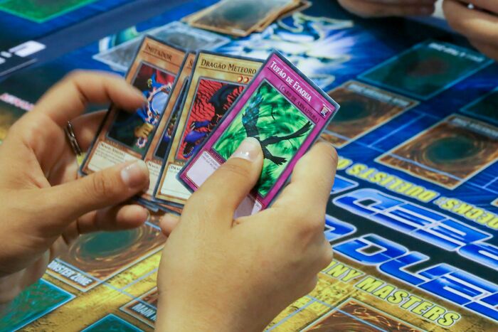 Hands holding trading cards in a game, symbolizing old friends reconnecting