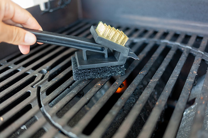 Hand cleaning barbecue grill with brush for uncommon jobs