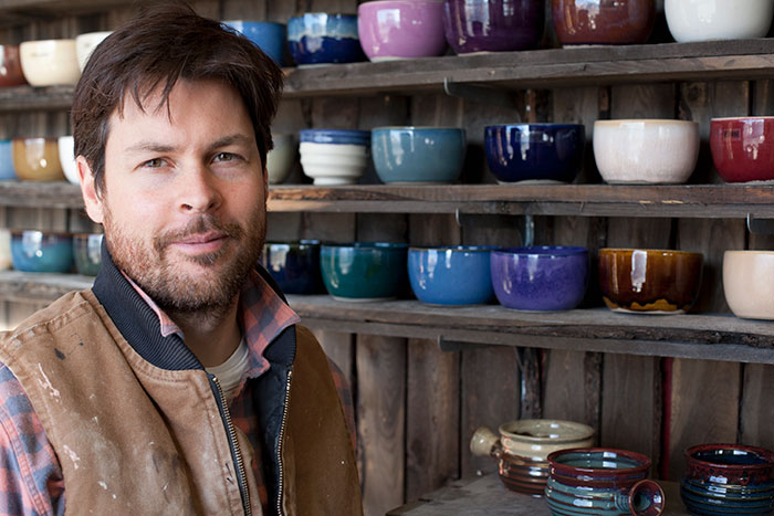 Man posing in front of shelves with bowls in unusual jobs setting