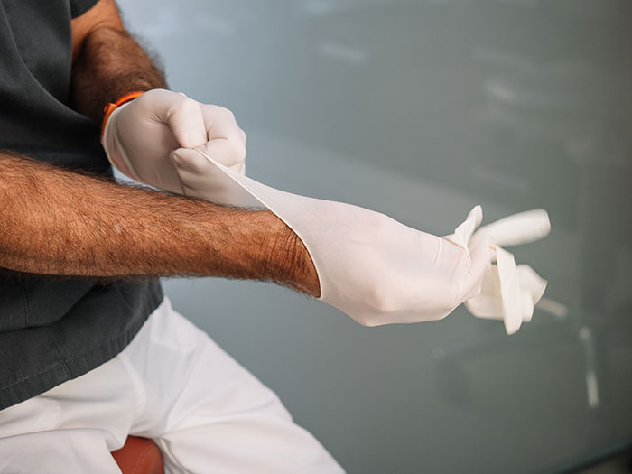 Person putting on white gloves in medical or unusual job setting
