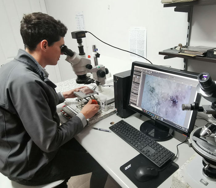 Man examining sample under microscope in strange jobs laboratory setting