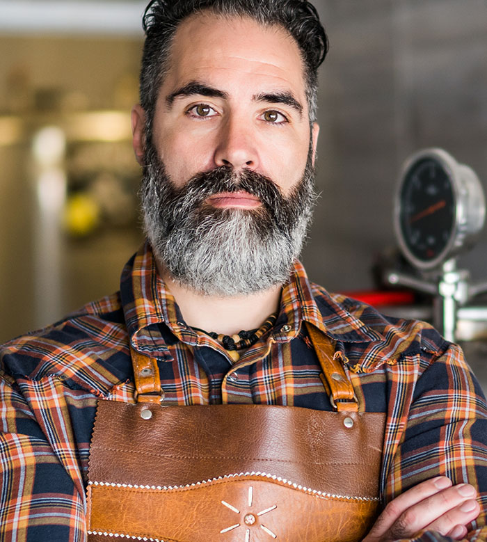 Bearded man wearing leather apron in a workshop representing strange jobs
