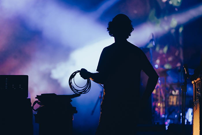Silhouette of stagehand holding cables during concert setup