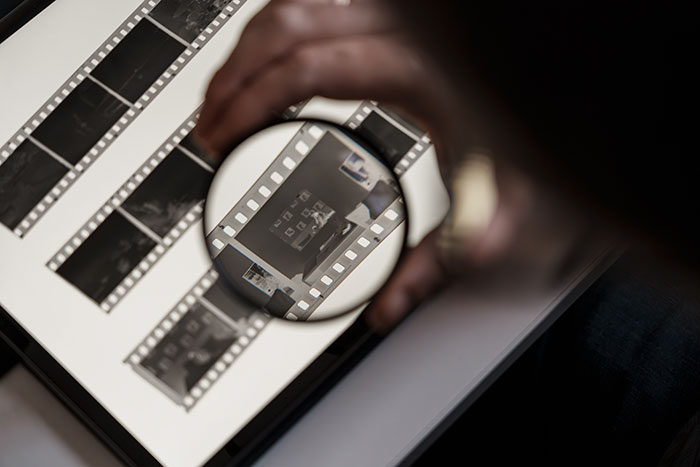 Magnifying glass inspecting photographic film negatives on a lightbox
