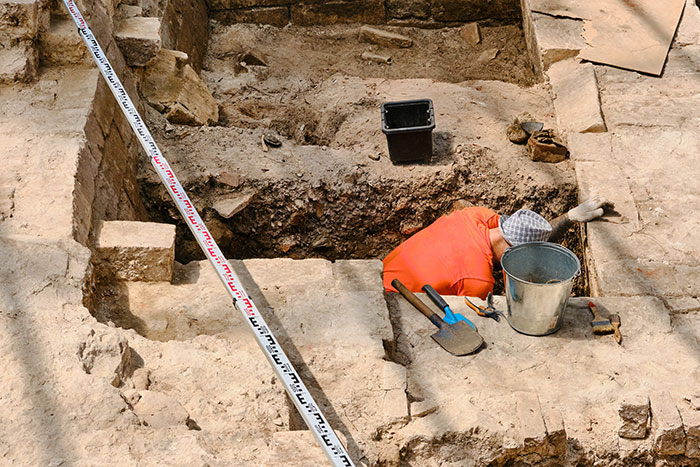 Archaeologist excavating site with tools showing unusual job in archaeology