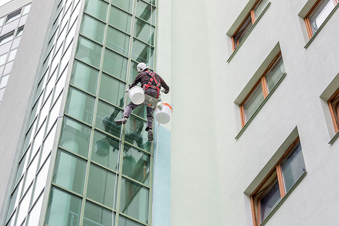Rope access technician cleaning high-rise building windows