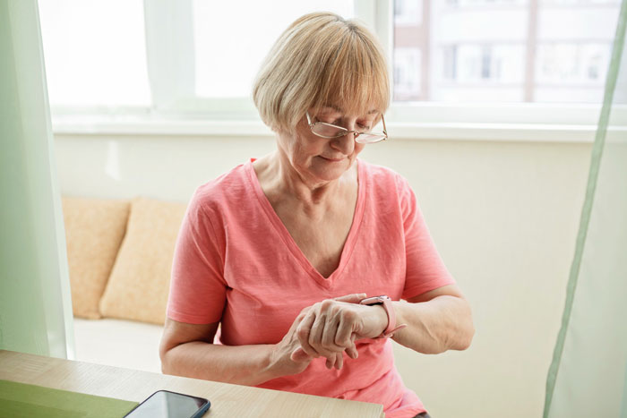 Older woman looking at smartwatch, symbolizing woman enduring snide comments from MIL Older woman looking at smartwatch, symbolizing woman enduring snide comments from MIL
