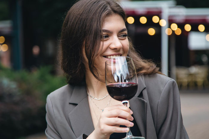 Smiling woman holding a glass of red wine enjoying a moment outdoors Smiling woman holding a glass of red wine enjoying a moment outdoors