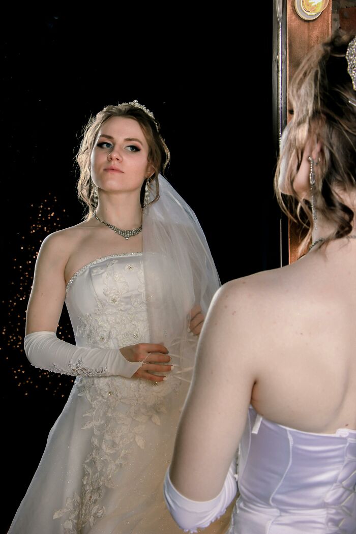 Bride in wedding dress looking at herself in mirror