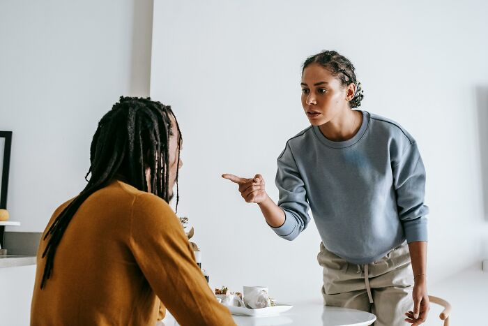 Woman pointing finger and arguing with a seated man