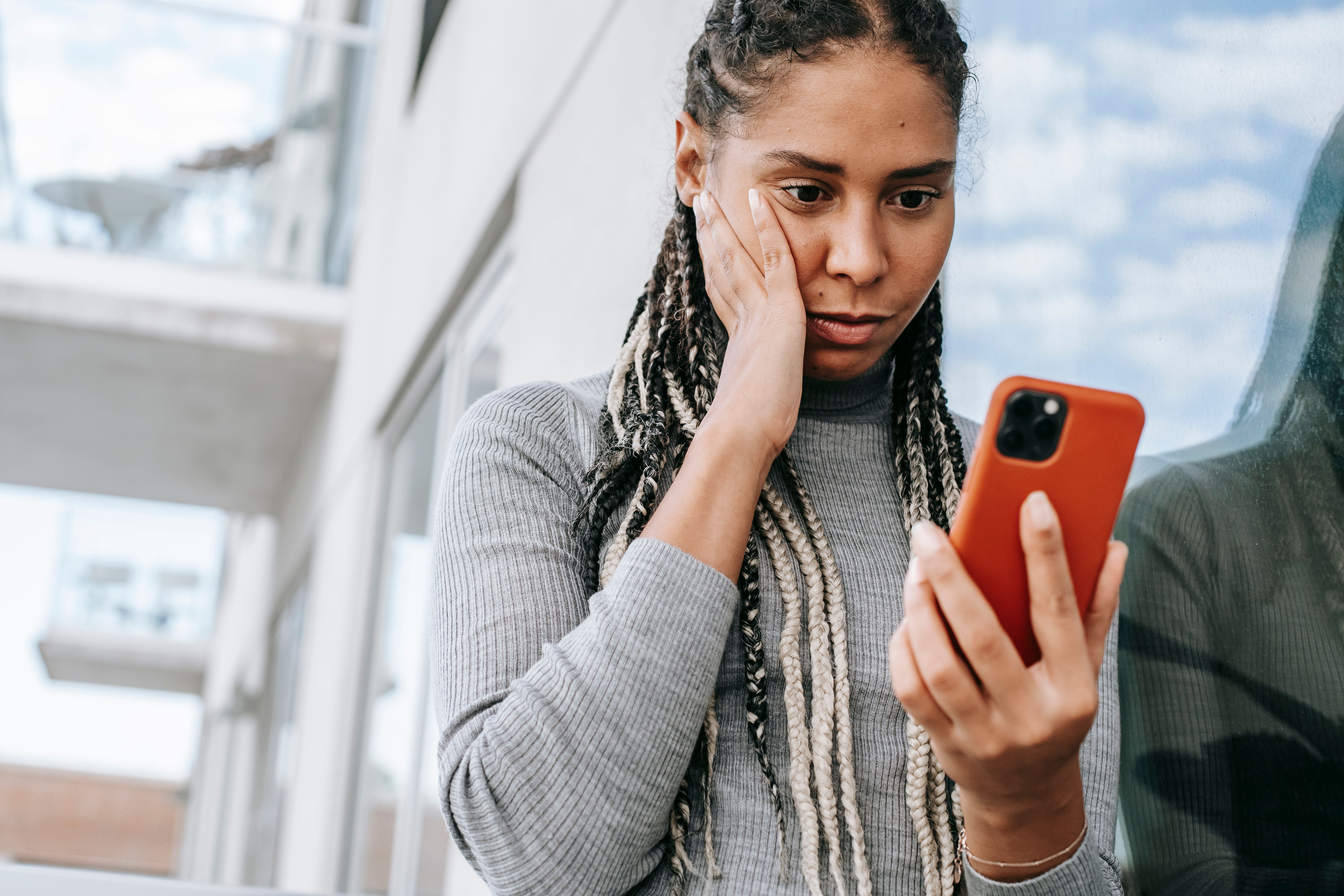 A woman looking shocked while holding a smartphone. She appears to be reacting to an ex trying to embarrass her.