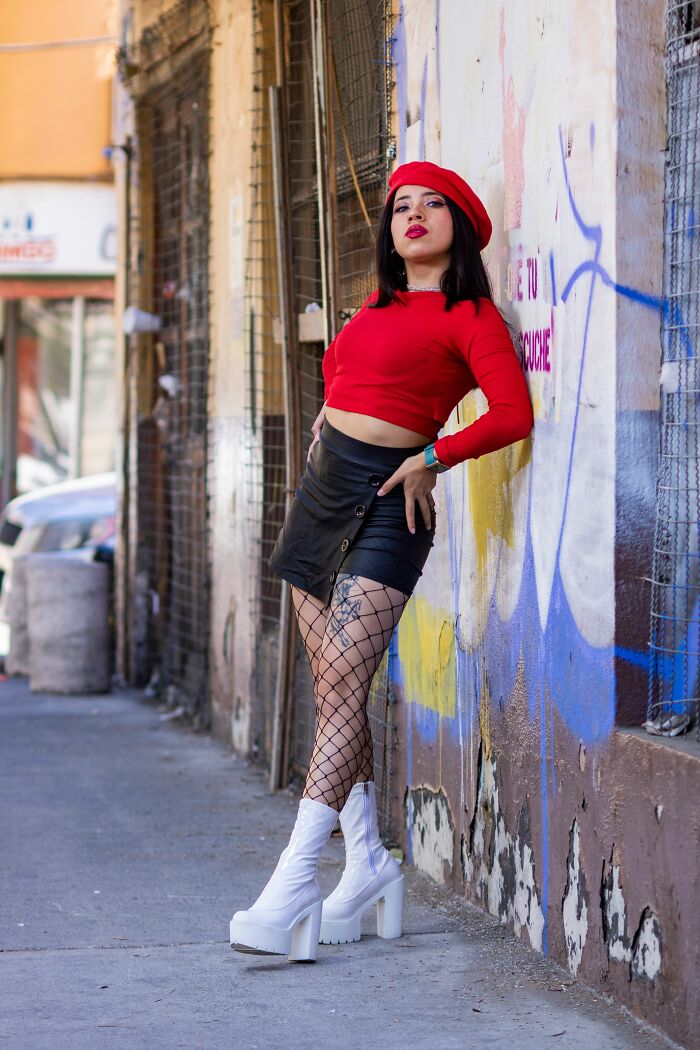 Woman in a red top and beret, posing against a wall, sharing her turn offs.