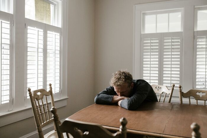 Man sitting alone at table looking down, reflecting on cheating moments