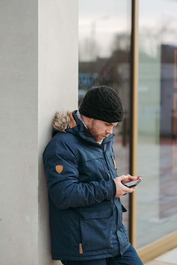 Man in a blue jacket looking at his partners phone. He looks like he found some worst things on the phone.