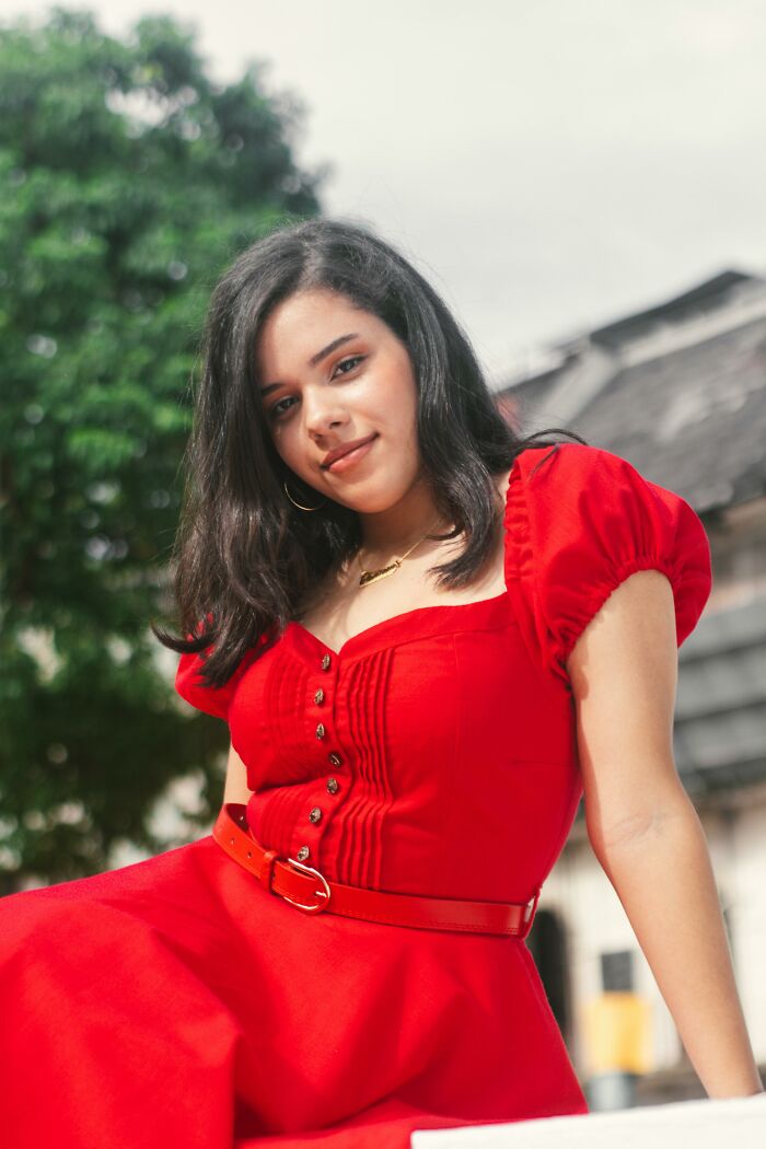 Young woman wearing red dress sitting outdoors