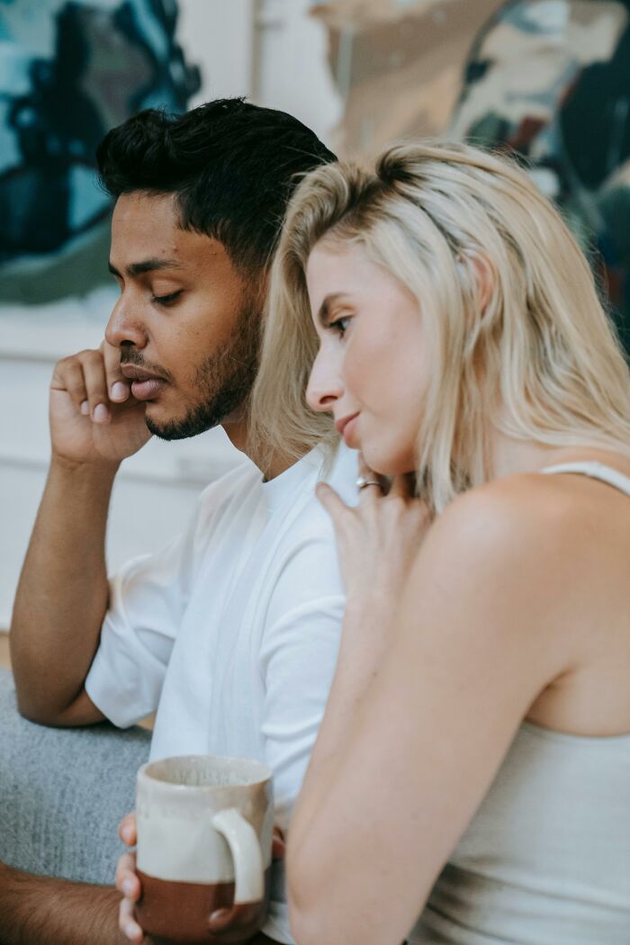 Couple having a serious conversation holding coffee in a home setting