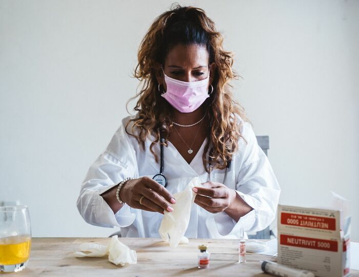 A doctor wearing a mask and gloves prepares for an awkward situation, misreading social cues in a medical setting.