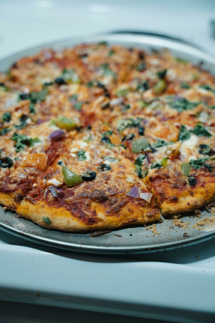 Freshly baked vegetable pizza with olives, peppers, and onions on a tray