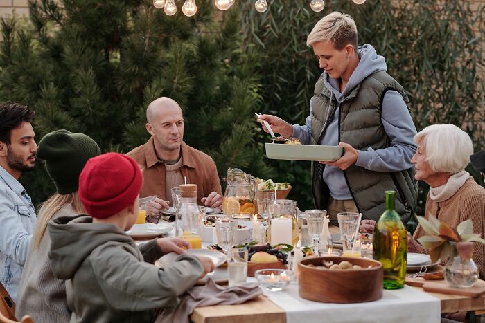 A family gathered around a dinner table outdoors, sharing a meal and stories from polygamist families.