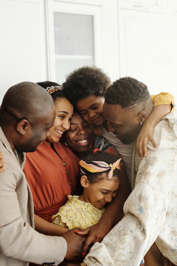 A diverse family embraces, sharing a moment of joy and connection, a contrast to the struggles of polygamous families.