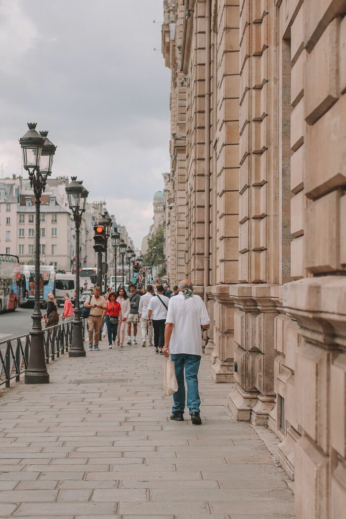 People walking on a busy city sidewalk next to a grand building, illustrating everyday wild coincidences.