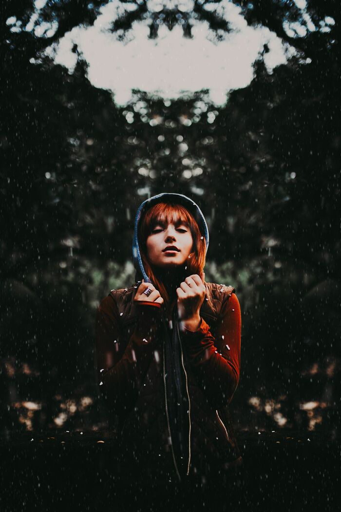 A woman with red hair in a hoodie, surrounded by a dark, reflective environment, showing experiences people can't explain.
