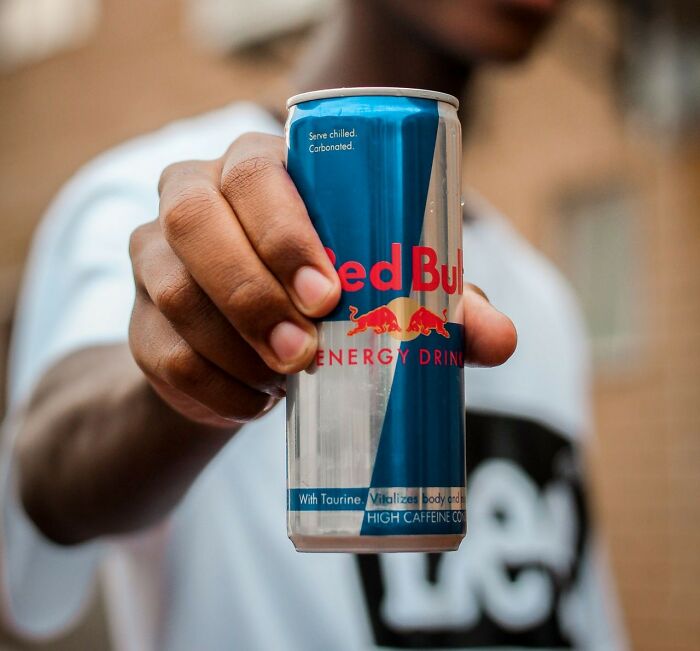 Hand holding a Red Bull energy drink, symbolizing a quick fix for intense stress and burnout.