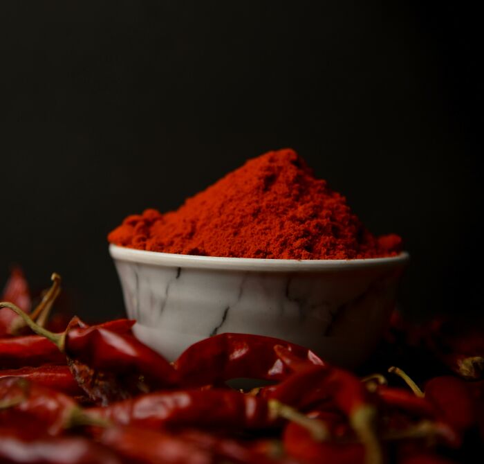 Bowl of red chili powder with dried red chilies around