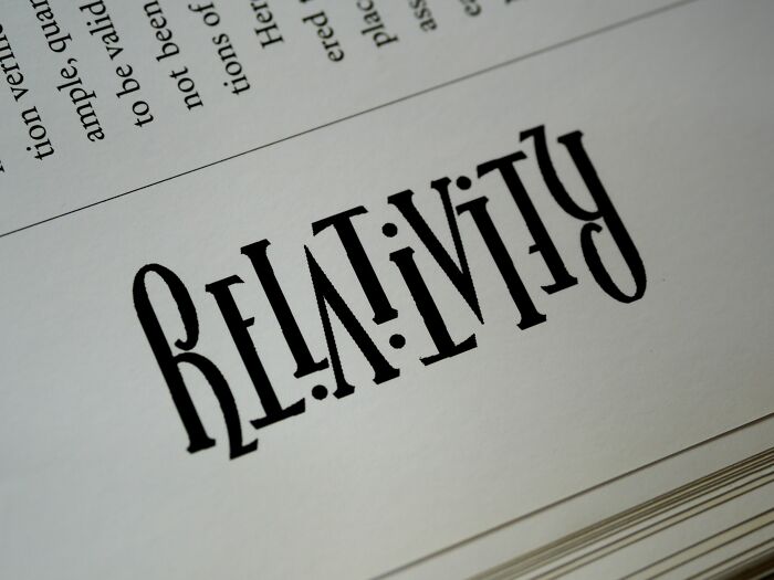 A close-up of the word RELATIVITY printed upside down on a page, part of a collection of math rebus puzzles.