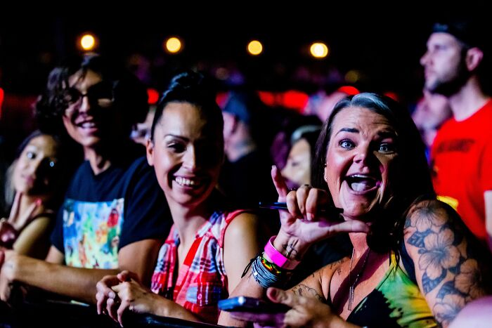 People smile and pose at a concert, a fun environment where misread social cues can become super awkward.