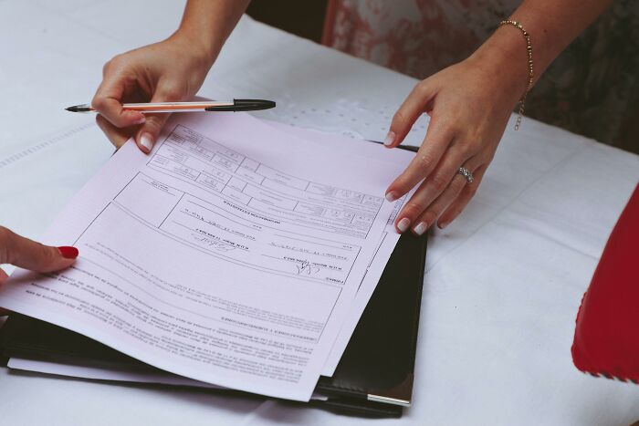 Hands holding wedding documents with pen on a table for bride registration