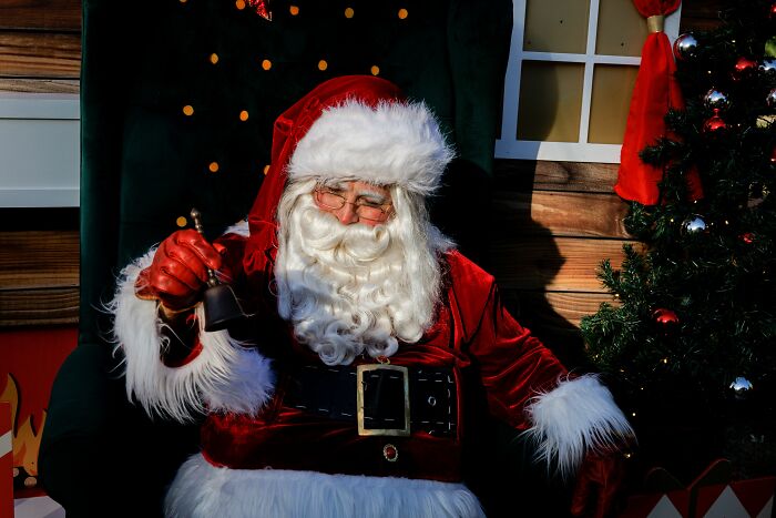 Santa Claus sitting in a chair, holding a bell, symbolizing hidden true selves behind a known persona.