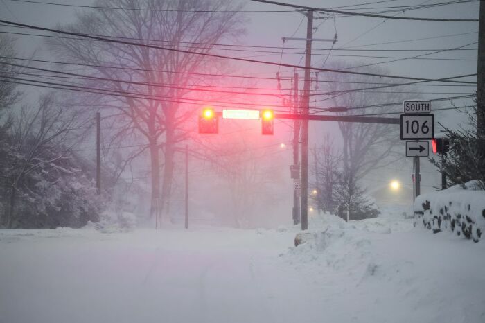 A snowy road with red traffic lights and power lines, creating an atmosphere for experiences people can't explain.