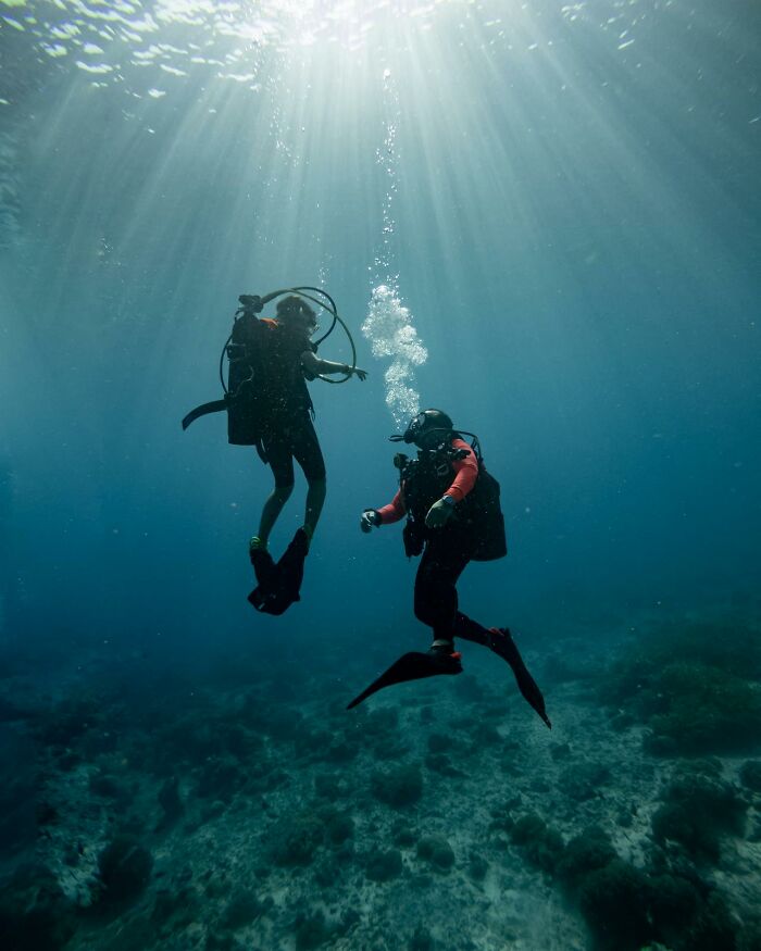 Two scuba divers underwater with sunlight rays above