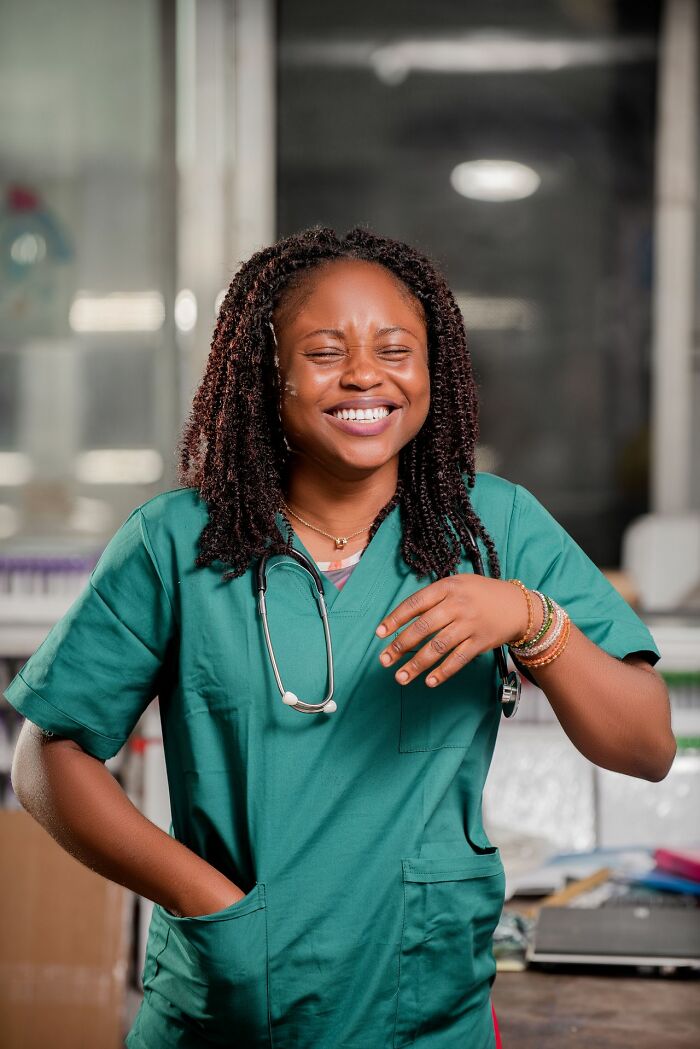 A smiling young woman in green scrubs with a stethoscope around her neck, embodying the spirit of healthcare workers during ER visits.